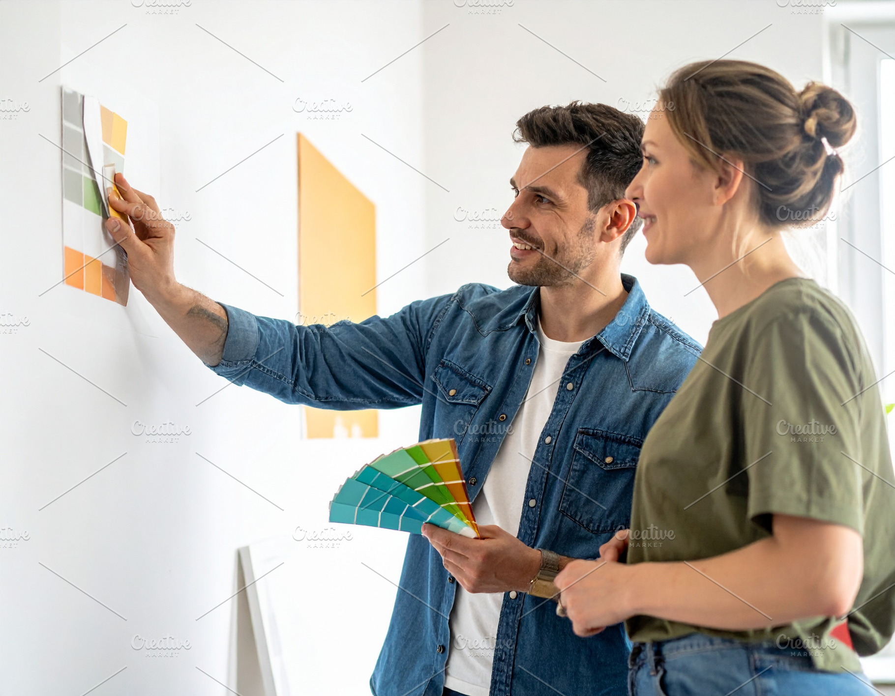 Home decorator showing wall paint samples to homeowners inside a, a Person Photo by DanFLCreativo