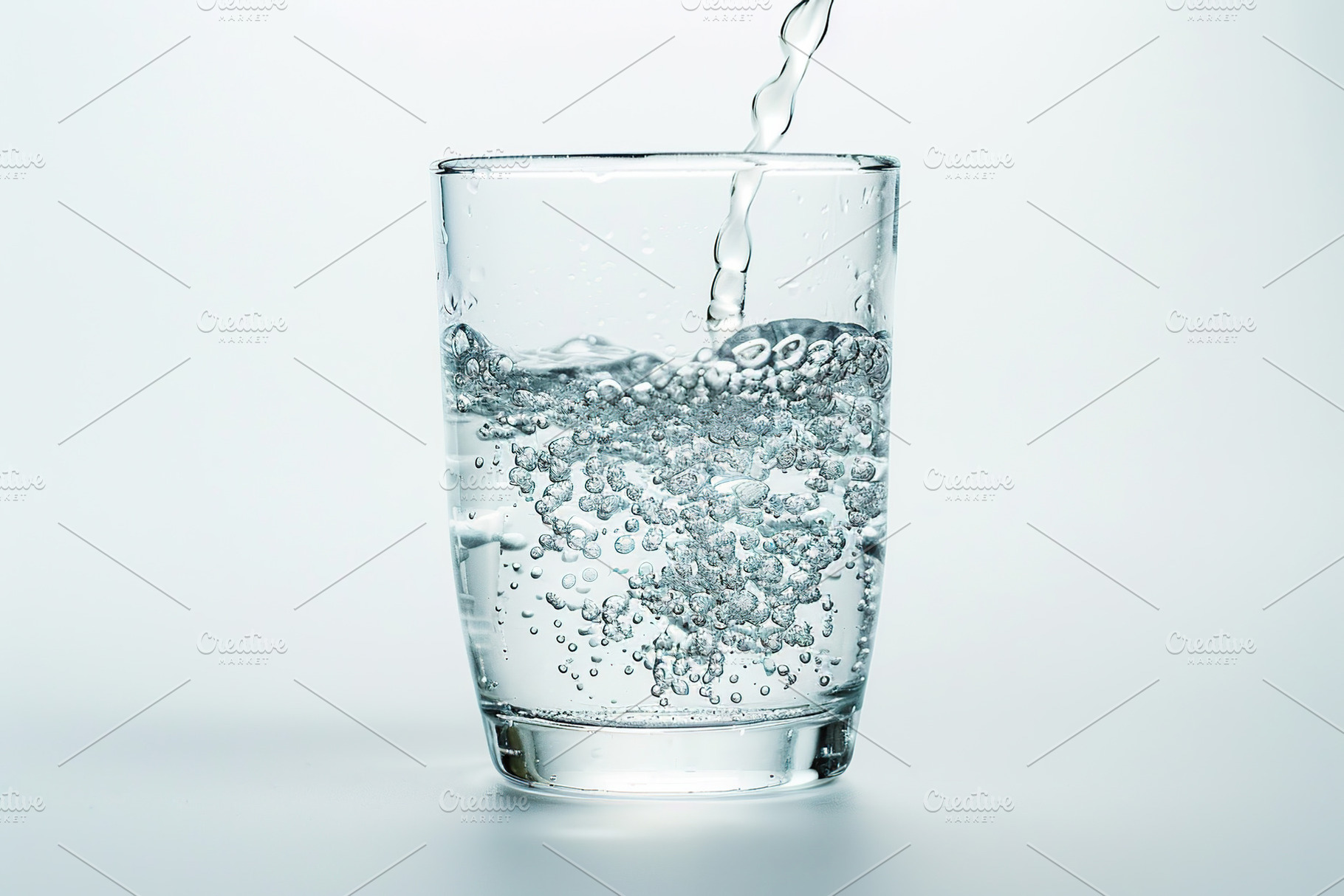 Pouring water into glass on white background, a Photo by AlyaAnd