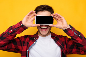 Excited guy covering eyes with empty smartphone screen