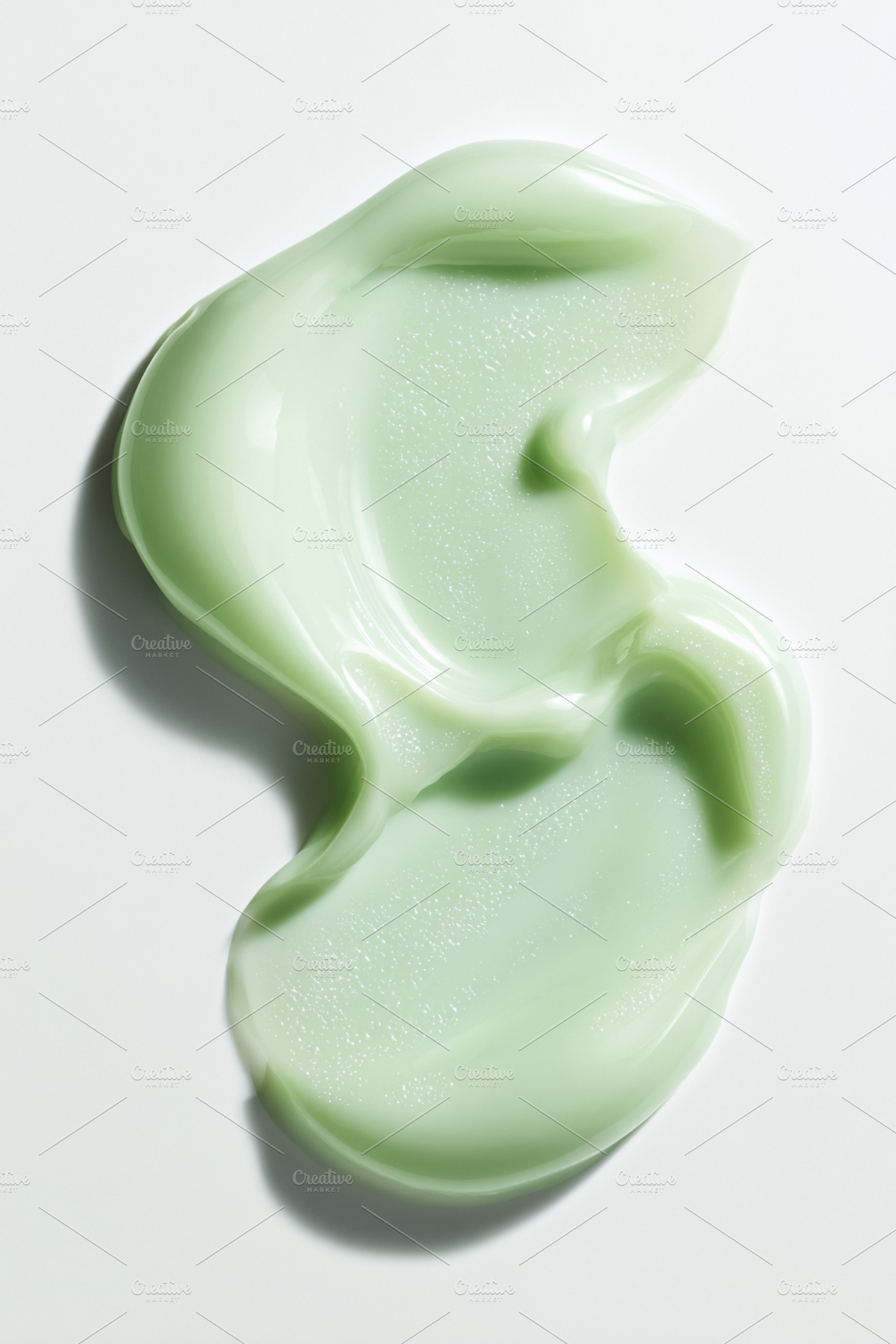 Green cosmetic cream dispensing on white background showing smoo, a Photo by Studio ANNA