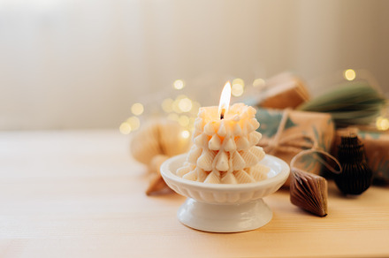 Burning candle shape of tree, gift boxes presents and Christmas decoration on w