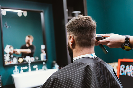 Man in barbershop sits in chair in front of mirror while profess, a Person Photo by progressman