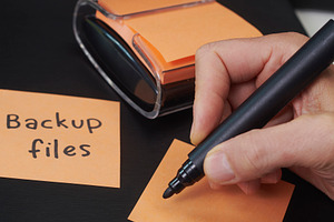 orange sticky note about to be written by a man, a Photo by Nito