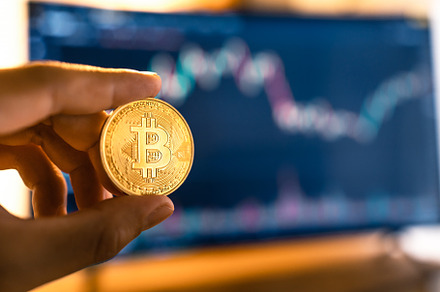 Bitcoin coins in hand in front of the computer, a Business Photo by Art Rachen