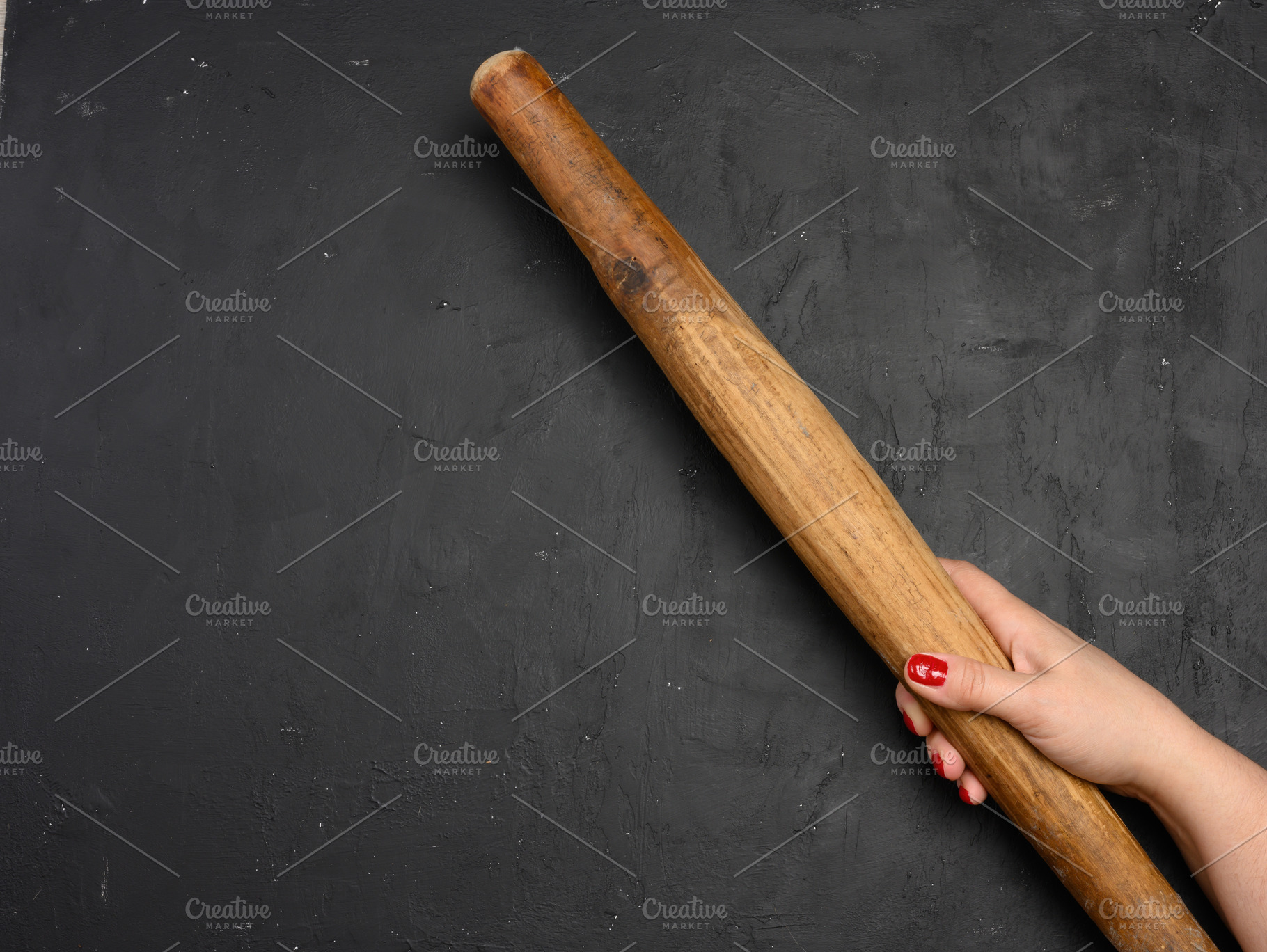 Female hand holding a vertical antique wooden rolling pin agains, a Food & Drink Photo by ndanko