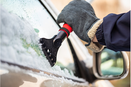 Hand in glove holding a snow scraper, a Transportation Photo by WildMedia