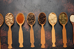 Various dried spices, seeds and roots in wooden spoons arranged, a Food & Drink Photo by ndanko