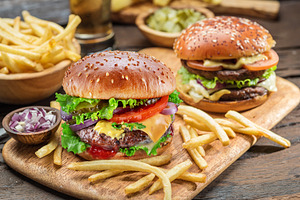 Hamburgers and French fries on the wooden tray., a Food & Drink Photo by Volff