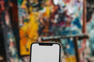 A person holding a blank smartphone iPhone mockup in front of a colorful abstra, an iPhone Mockup by Textures & Backgrounds