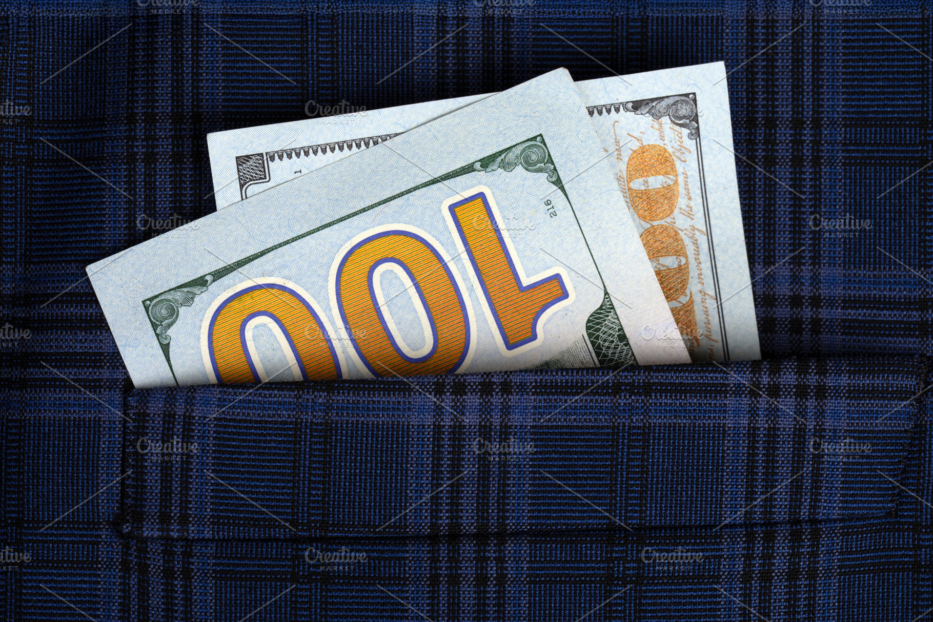 Close-up of two US hundred dollar bills sticking out of a blue plaid fabric poc, a Business Photo by Ales Munt