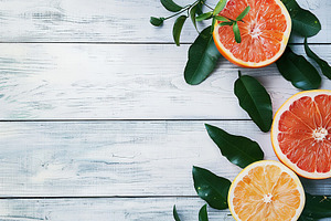 Fresh and tasty grapefruits and green leaves on wooden background, a Food & Drink Photo by AlyaAnd