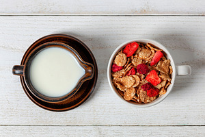 Healthy breakfast with milk and cereals with dried strawberries on white wooden, a Food & Drink Photo by Antonio Gravante Market