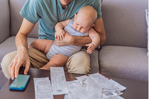Father sitting on sofa holding baby, a Business Photo by Elizaveta Galitskaya
