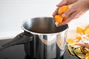 Hand adding chopped vegetables into pot on stove in home kitchen, a Food & Drink Photo by etorres69