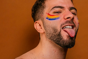 Young adult man smiling with rainbow face paint, a Photo by karrastock