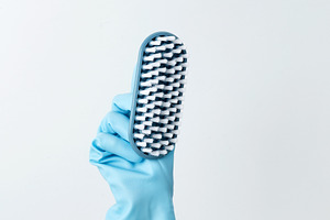 A hand in a blue rubber glove holding a cleaning brush, focused on cleaning tas, a Photo by matucha