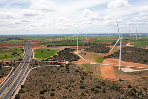 Aerial drone view of wind turbines on open fields next to highway