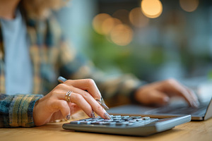 Woman using calculator and laptop fi, a Photo by Pixeness Studio