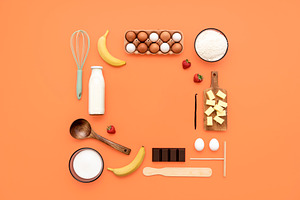Crepes ingredients and utensils flat lay on an orange table.