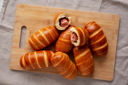 Homemade Sausage Buns on a bamboo board, top view. Flat lay, ove, a Food & Drink Photo by LiudmylaChuhunova