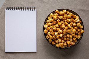 Homemade Caramel Pop Corn in a Bowl, blank notepad, top view., a Food & Drink Photo by LiudmylaChuhunova