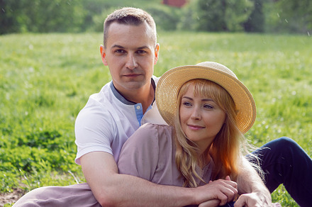 man and a woman in love in a dress and hat are sitting on a blanket on a green, a Person Photo by SaulichPhoto