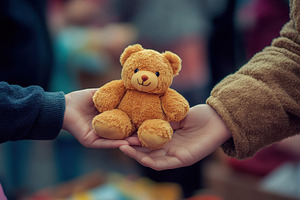 Child's hand receiving a teddy, a Photo by Pavel_design