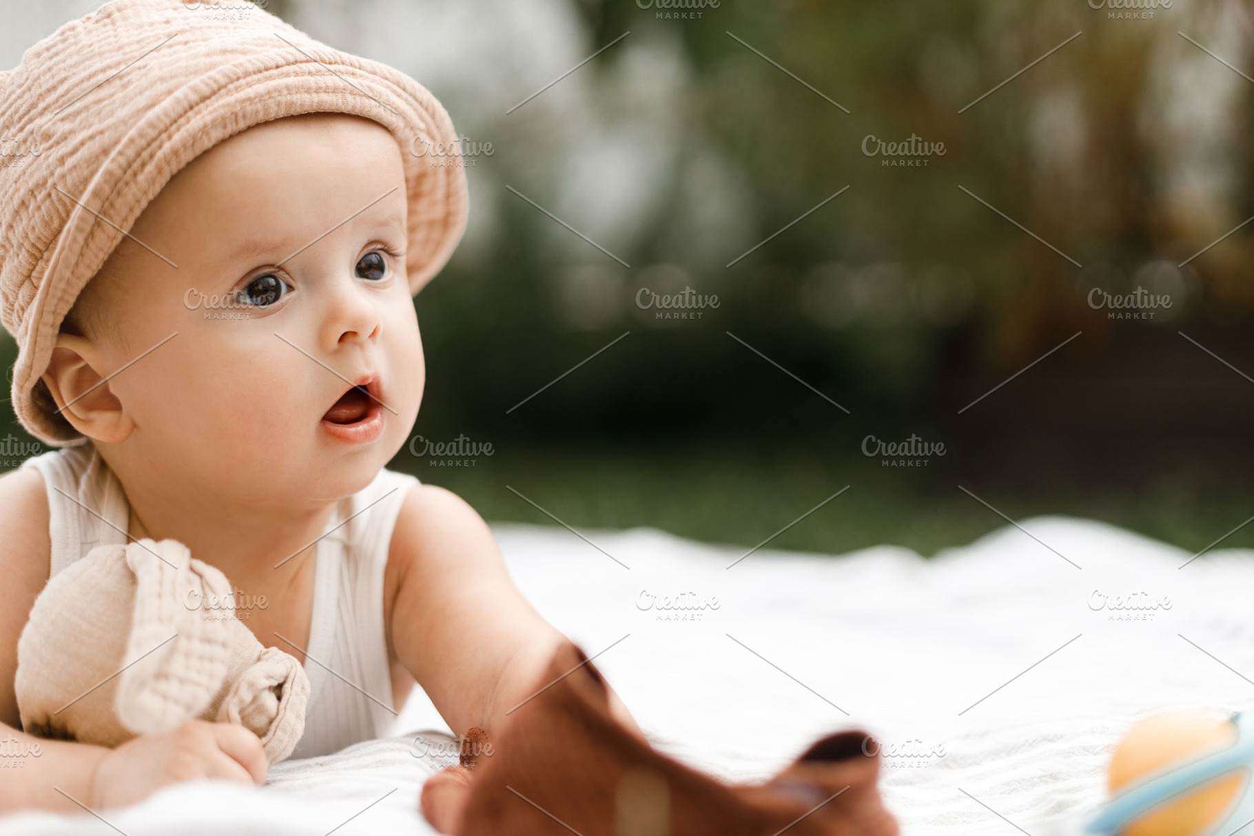 Beautiful happy baby in hat lying on blanket and playing with to, a Person Photo by Sonjachni