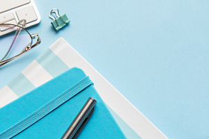 Office workspace with keyboard, notebooks, and blue supplies, a School & Education Photo by Olena Rudo