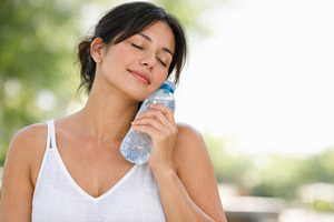 Woman cooling down with water bottle, a Photo by Dvoevnore photos