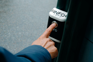 a man presses an outdoor public information button, a Photo by Nito