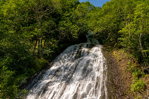 Waterfall flowing beneath bright sky, a Nature Photo by Elena Vagengeim