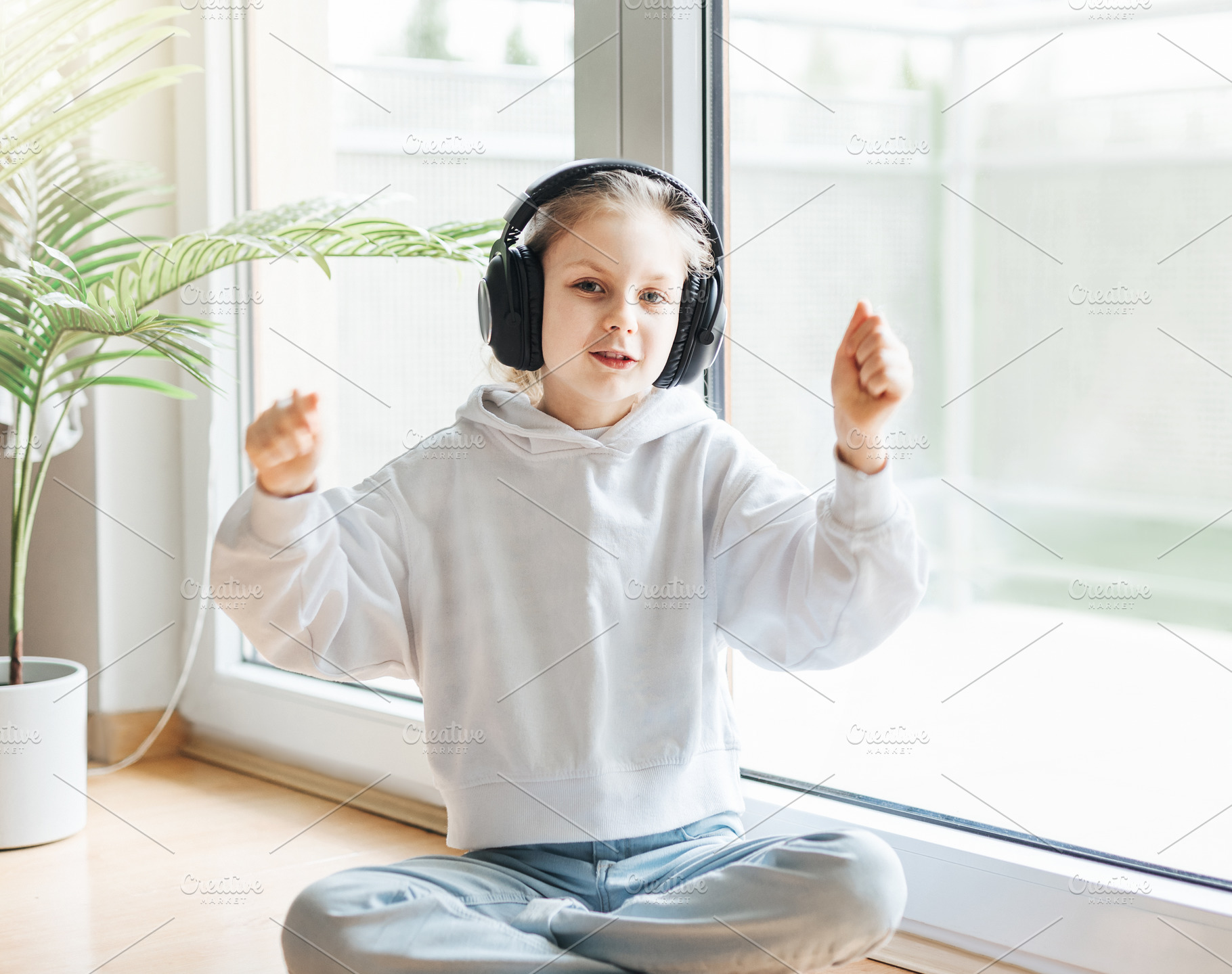 Cute little girl listening to music in headphones, a Person Photo by Olena Rudo