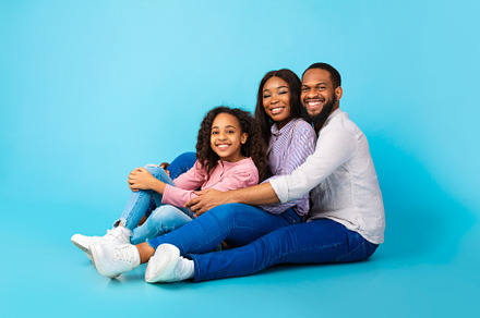 African American man hugging his smiling wife and daughter, a Background Photo by Prostock-Studio