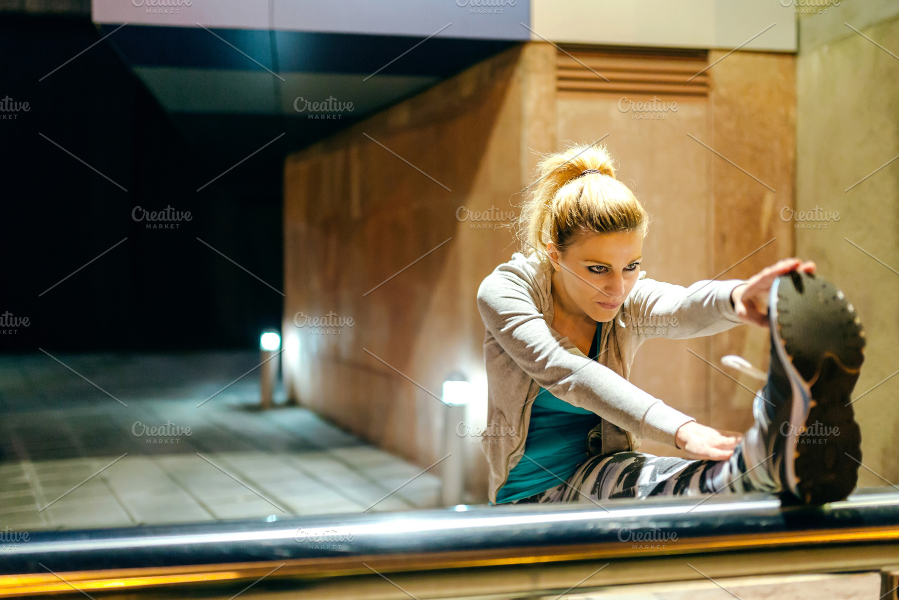 Woman runner stretching her legs before training at night on tow, a Sports & Recreation Photo by davidpereiras