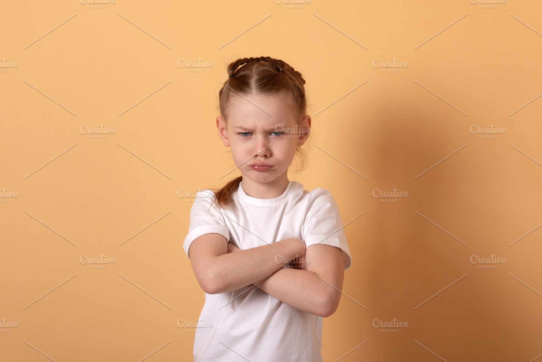 Young girl with braided hair standing against a beige background, a Person Photo by Ales Munt