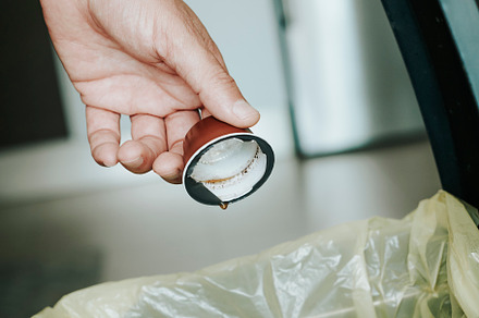 man throwing a coffee capsule to the dustbin, a Photo by Nito