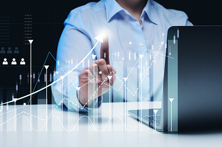 woman sits at a laptop in front of a holographic chart with gro, a Business Photo by ndanko