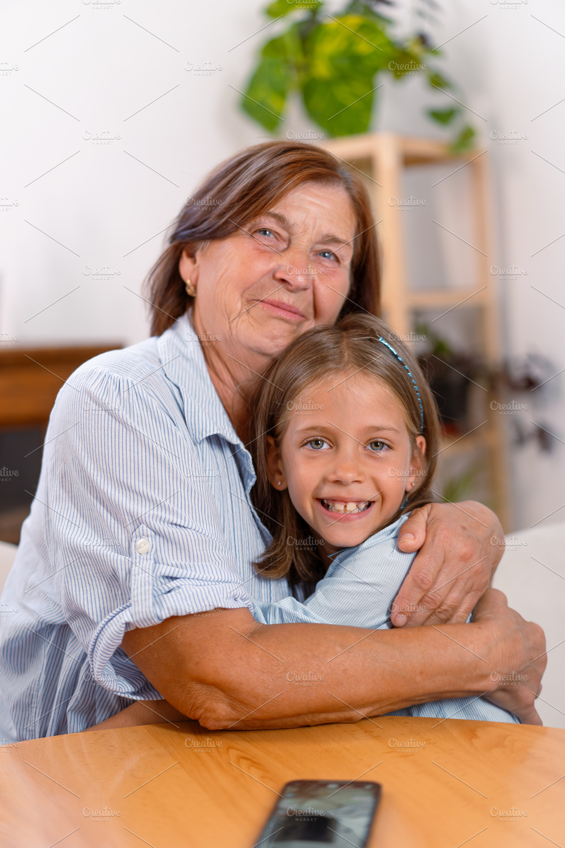 Contented grandmother and granddaughter embracing each other at home, a Photo by andreonegin market