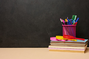 A stack of colorful books, a pink glass with pens and pencils, a, a School & Education Photo by ndanko