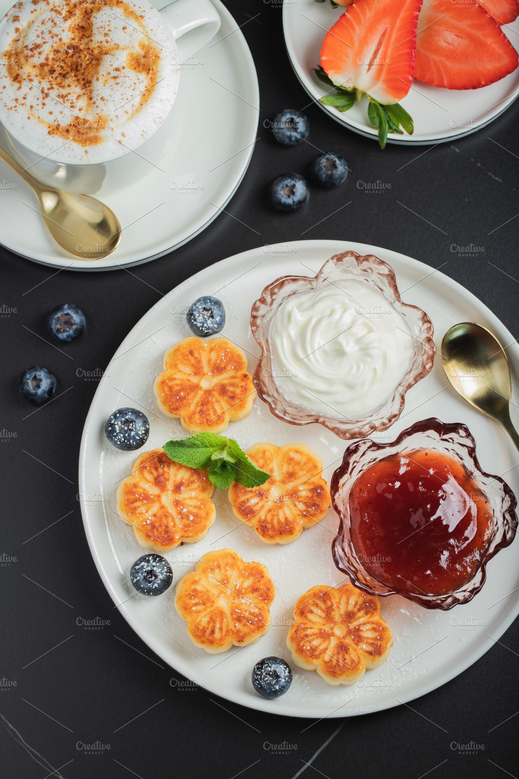 Cottage cheese pancakes, syrniki, curd fritters decorated with strawberry and r, a Food & Drink Photo by Budarinphoto