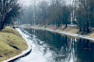 A tranquil river scene with calm water reflecting trees and a cloudy sky, surro, an Industrial Photo by Textures & Backgrounds