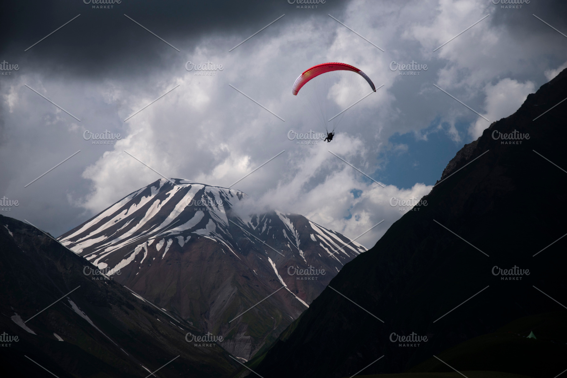 Paraglider flying over snow covered mountains under storm clouds, a Photo by Pictures for you!!!!!!!!!