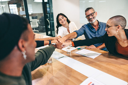 Successful businesspeople bringing their fists together in a boardroom, a Person Photo by Jacob Lund