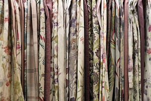 Diverse fabric samples hanging, displaying floral and nature inspired patterns, a Photo by Studio ANNA