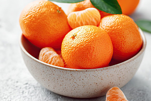 Peeled mandarin segments and whole fruit arranged in a smooth ceramic bowl for, a Food & Drink Photo by AlyaAnd