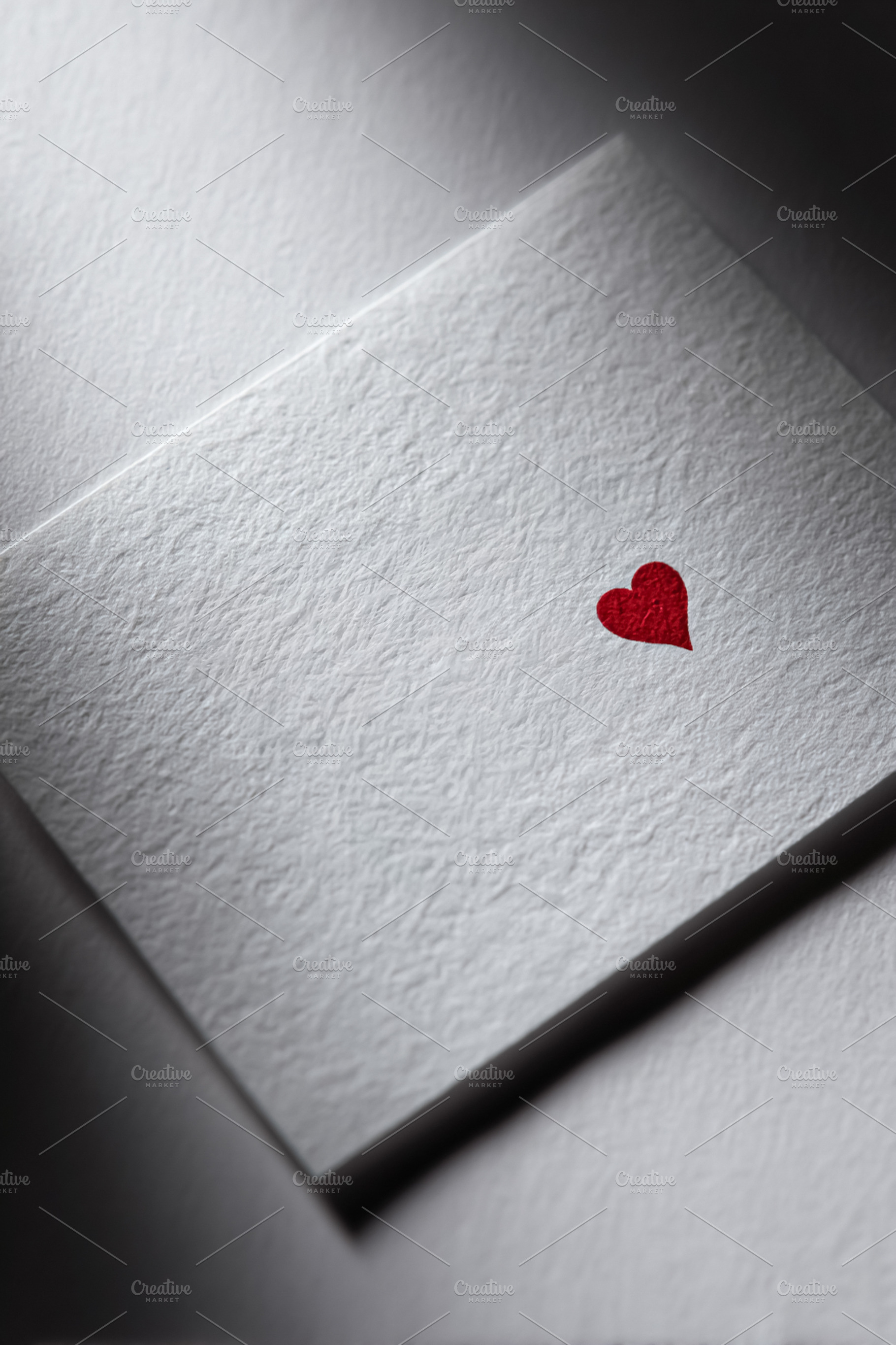 Minimal white textured card showing small red heart, symbolizing, a Photo by Studio ANNA