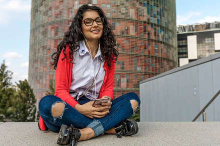 Young female hipster in stylish clothes and glasses with phone in hand sitting, a Person Photo by 2Design