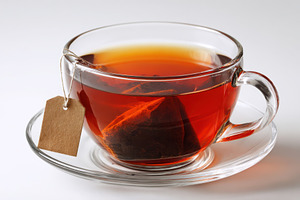 A glass cup of tea with a tea bag an, a Photo by Pixeness Studio