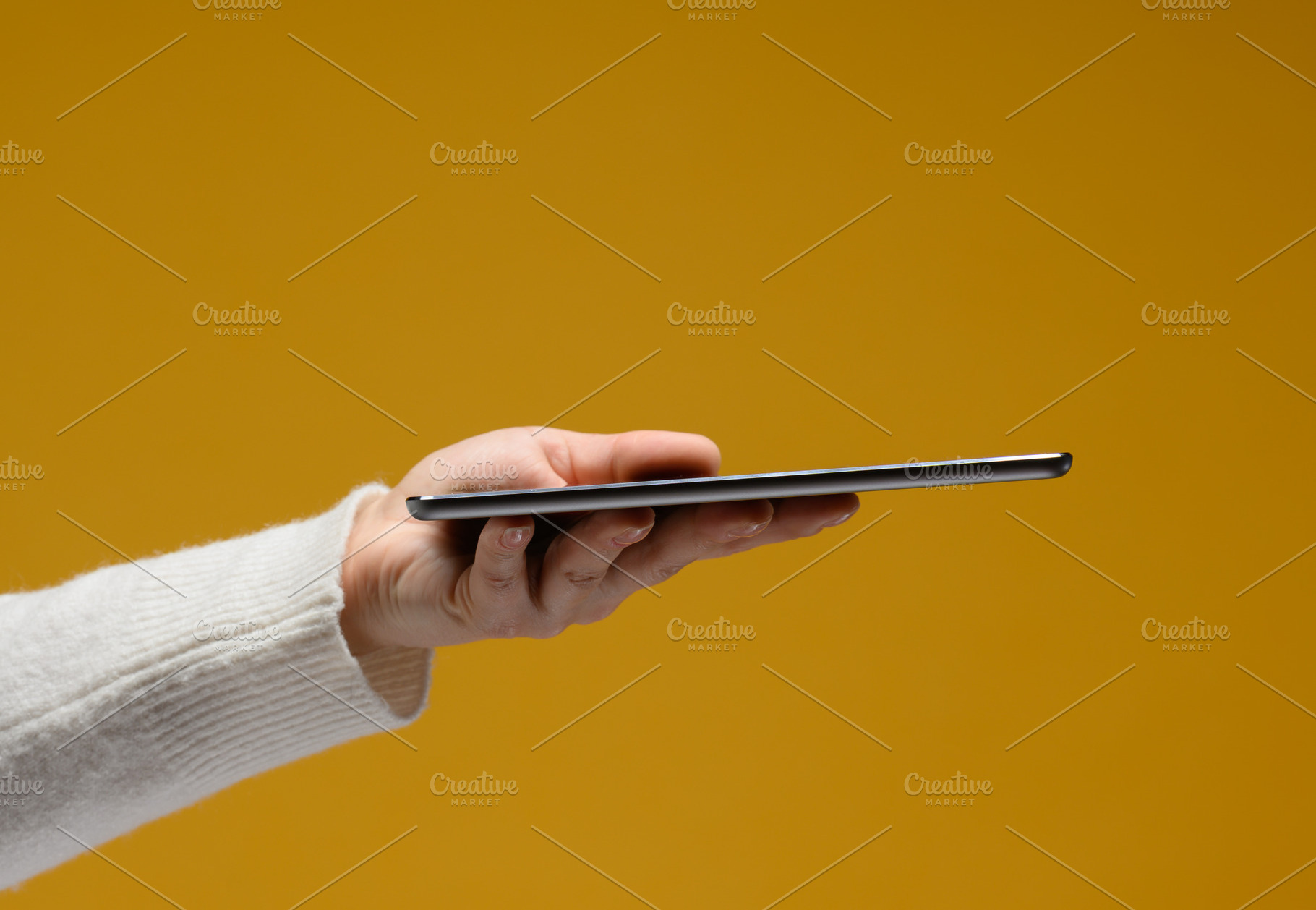 A hand in a white sweater holds a thin modern tablet horizontall, a Technology Photo by ndanko